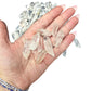 A handful of small Clear Quartz points held in an open palm for scale against the loose pile