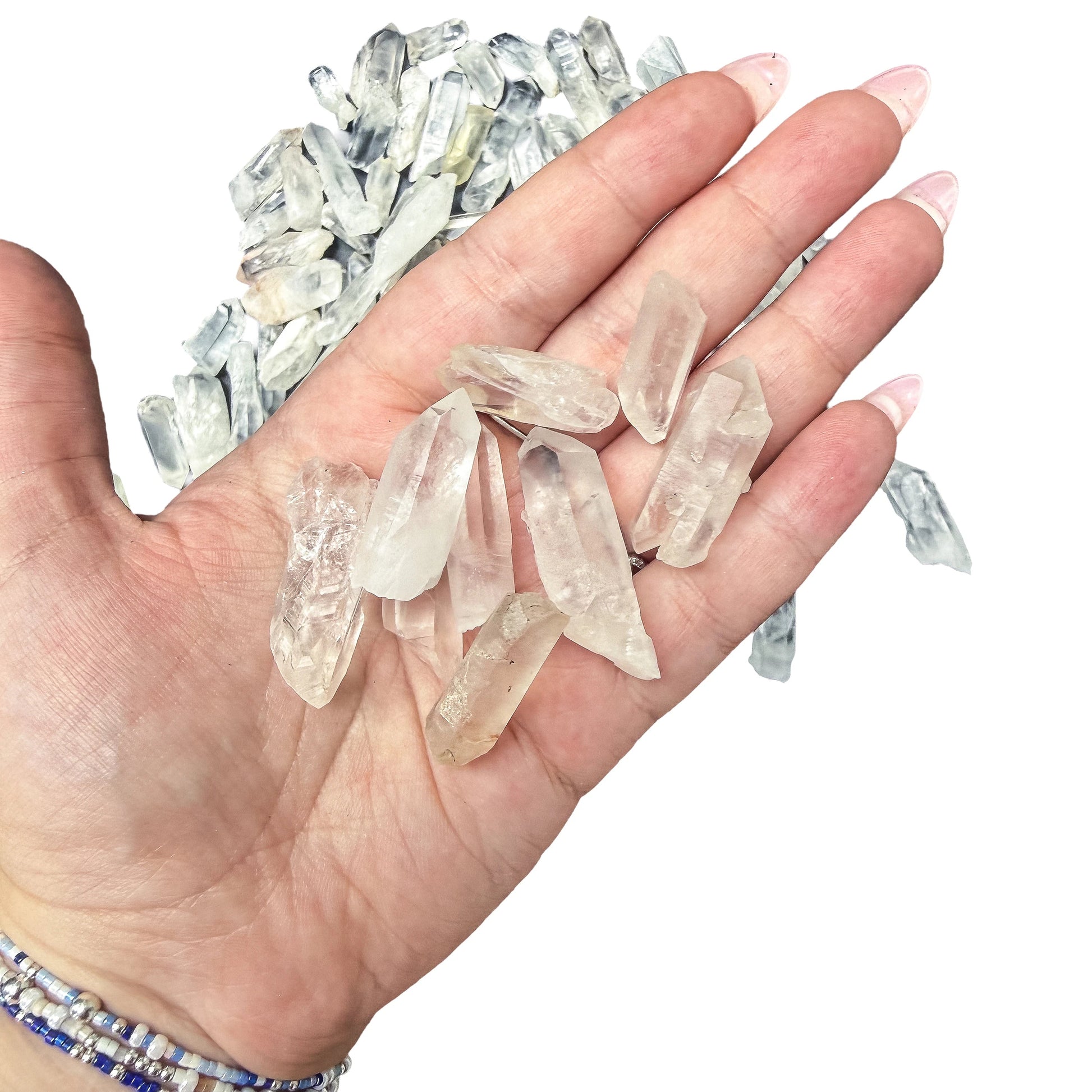 A handful of small Clear Quartz points held in an open palm for scale against the loose pile