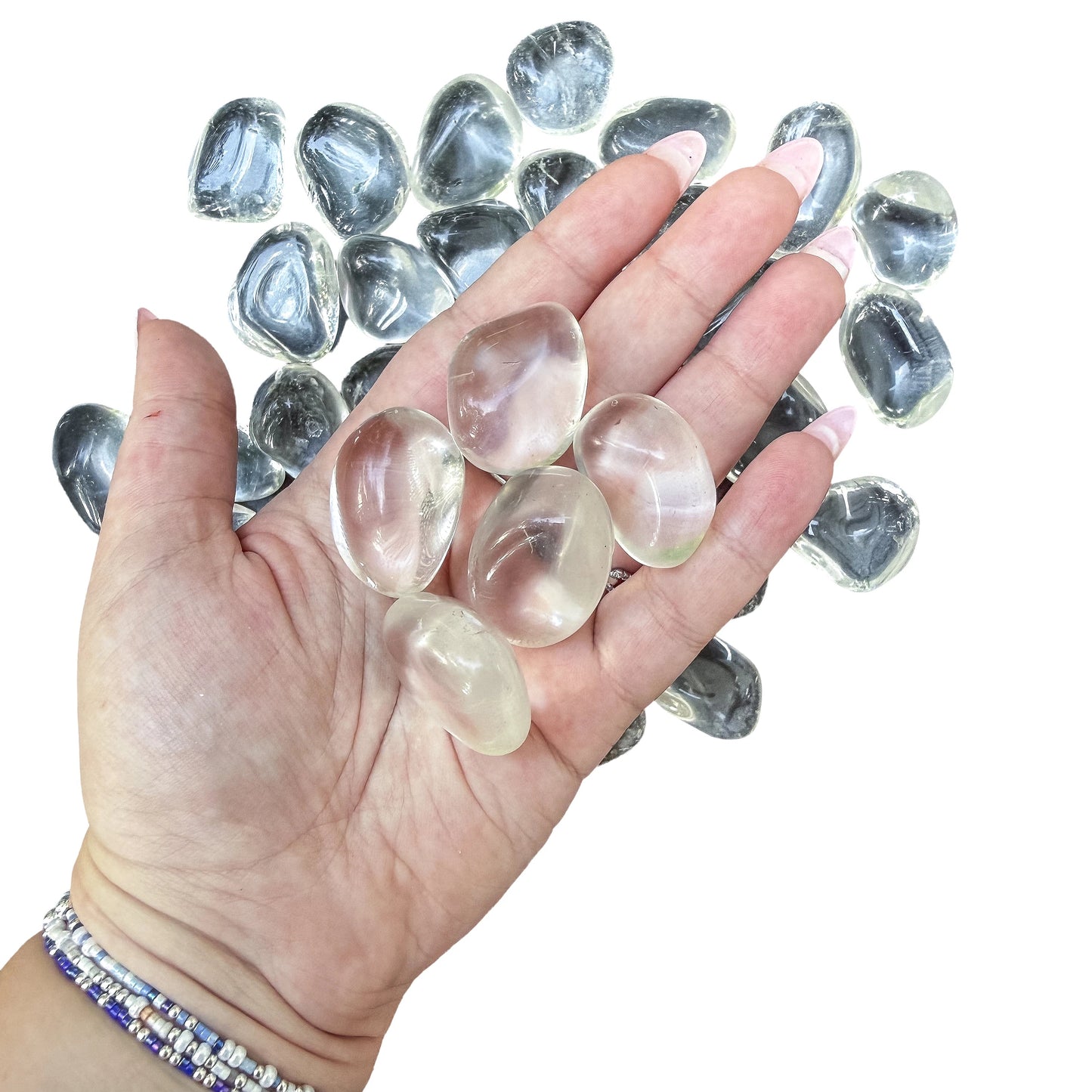 A handful of Clear Quartz tumbled stones held in an open palm for scale