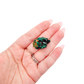 A 15.6 g dioptase, the emerald-green druzy, resting in an open palm for size