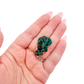 The compact sparkle held in a hand, showing the true scale of this 1.13 inch dioptase