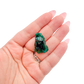 A 10.4 g dioptase, the rounded green cluster, resting in an open palm for size