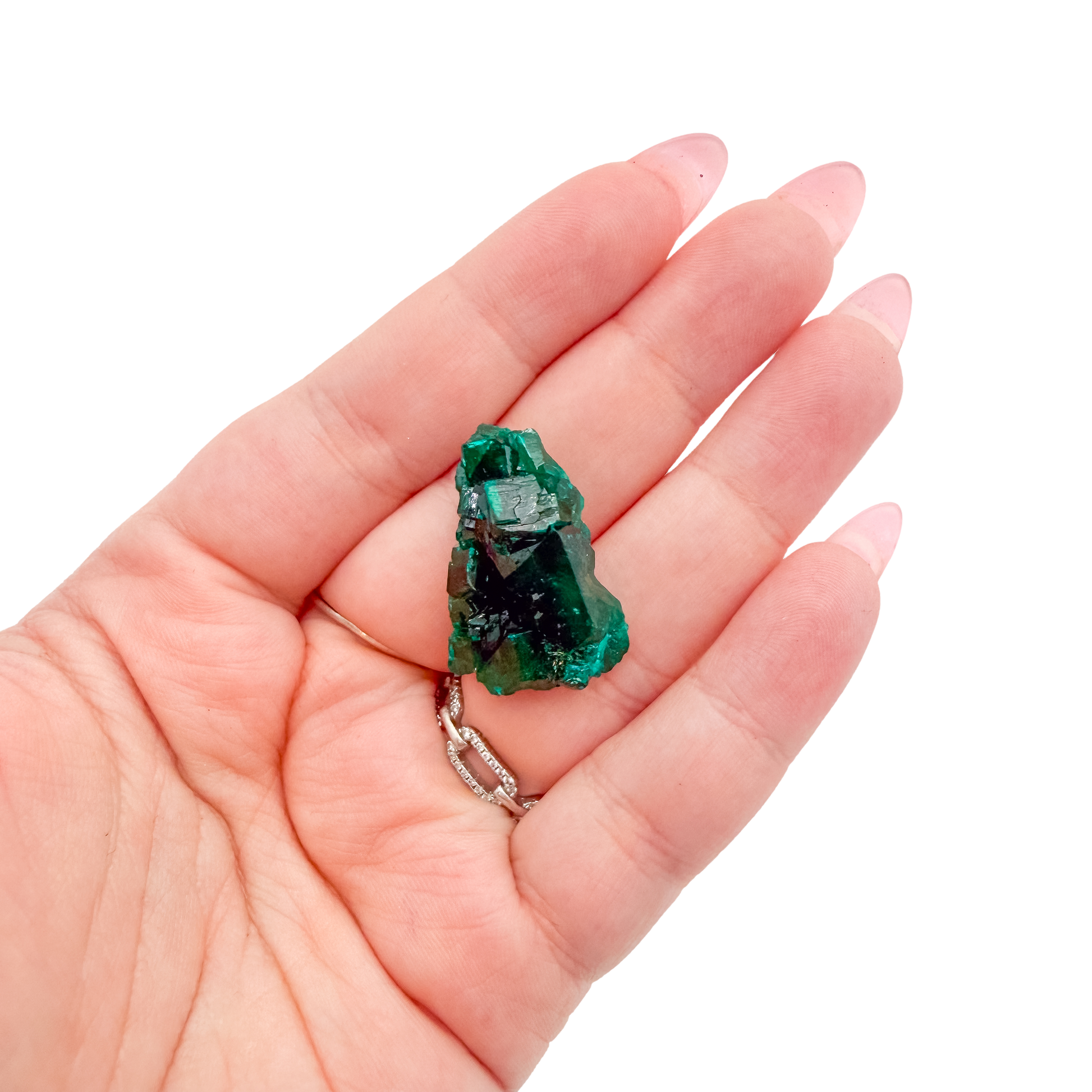 A 10.4 g dioptase, the rounded green cluster, resting in an open palm for size