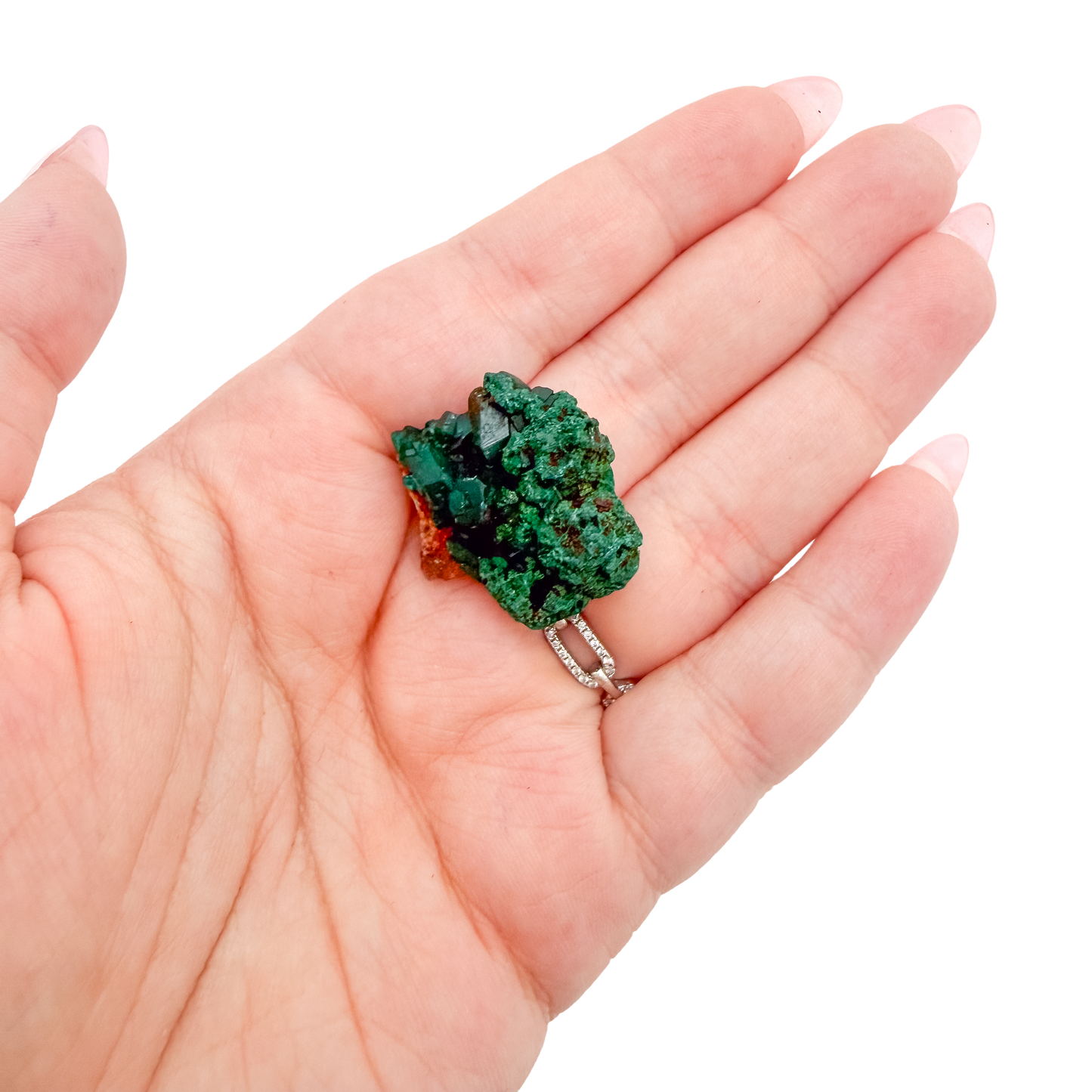 A 8.3 g dioptase, the cubic thumbnail, resting in an open palm for size
