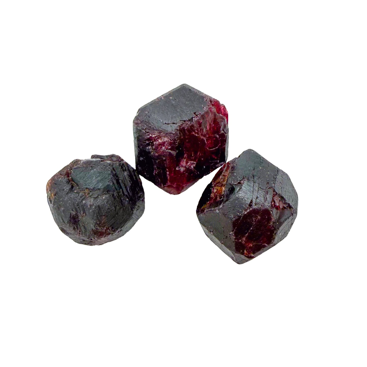 Three raw Garnet crystals close up, cherry red showing through the darker outer skin