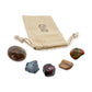 Grounding Crystal Kit: smoky quartz palm stone, hematite, garnet, petrified wood and unakite, arranged with the reusable cotton bag they come in, on white