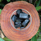 Grade aa black tourmaline raw held in hand for size reference