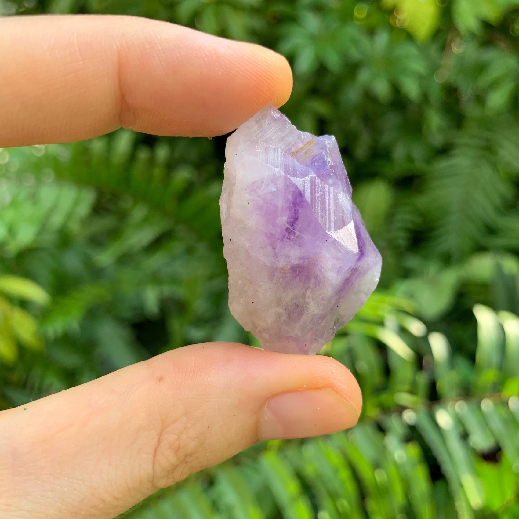 Set against a soft backdrop is an Amethyst raw crystal, from Anosy, Madagascar, with weight visible in the palm.