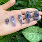 Held in hand, one Chevron Amethyst raw stone for scale, Zambia-sourced.