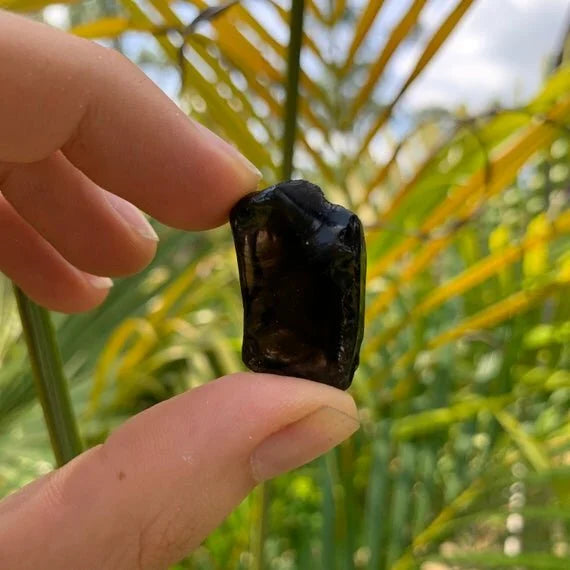 Opposite side of Apache Tear raw stone, showing natural patina, often paired with practices around Grounding.