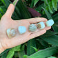 Hand-held view of a single Blue Opal tumbled stone sourced from Peru.