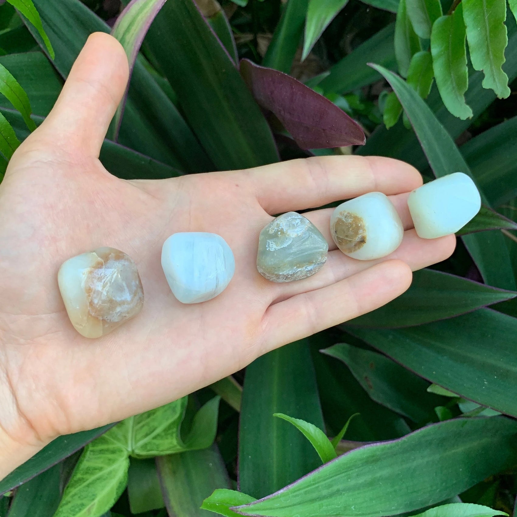 Hand-held view of a single Blue Opal tumbled stone sourced from Peru.