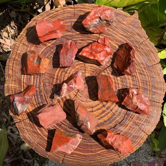 On a soft surface rests a Red Jasper raw crystal, shown for shape and scale.