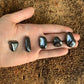 Edge-on view of gray Hematite tumbled stone, traditionally used for Grounding and Protection, showing natural inclusions.