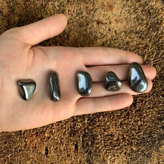 Edge-on view of gray Hematite tumbled stone, traditionally used for Grounding and Protection, showing natural inclusions.