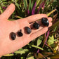 Hand-held view of one Apache Tear raw stone for scale, from Arizona, United States.