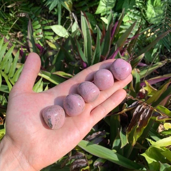 Companion image of Rhodonite tumbled stone, linked to Emotional Healing, set against a soft neutral surface.