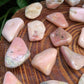Detail shot of Grade A Pink Opal tumbled stone under natural light