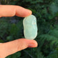 Held in hand is a Prehnite tumbled stone, linked to Manifestation, set against a soft neutral surface.