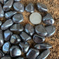 Underside view of gray Hematite tumbled stone, sourced from Minas Gerais, Brazil, carried for Grounding.