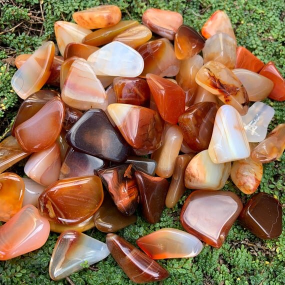 Daylight detail of Carnelian tumbled stone, from Boeny, Madagascar, shown in a calm studio setting.