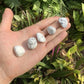 On a soft surface rests a Howlite tumbled stone, from Masvingo, Zimbabwe, associated with Cleansing, showing natural surface character.