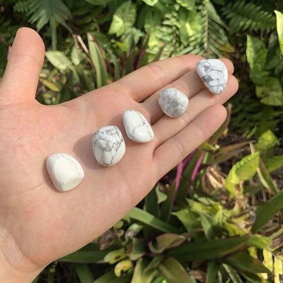 On a soft surface rests a Howlite tumbled stone, from Masvingo, Zimbabwe, associated with Cleansing, showing natural surface character.