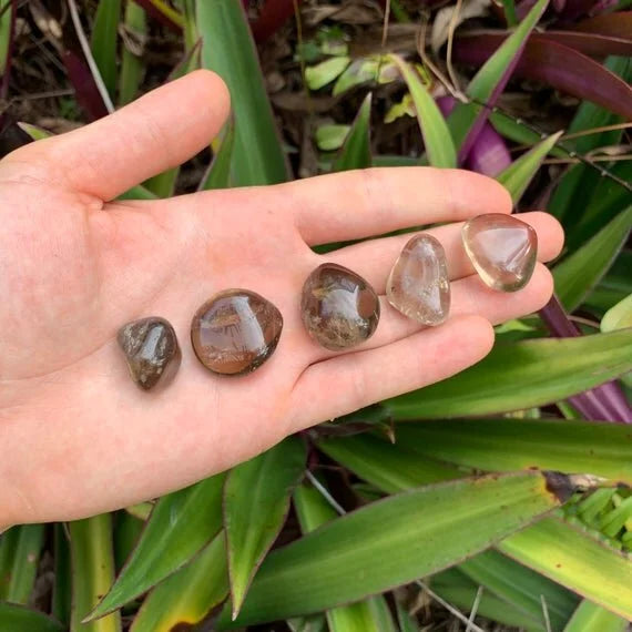 Open-palm view of Smoky Quartz tumbled stone, from Minas Gerais, Brazil, with depth visible across the surface.