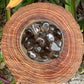 Top view of Grade AAA Smoky Quartz tumbled stone, showing natural variation, often worked with for Grounding.
