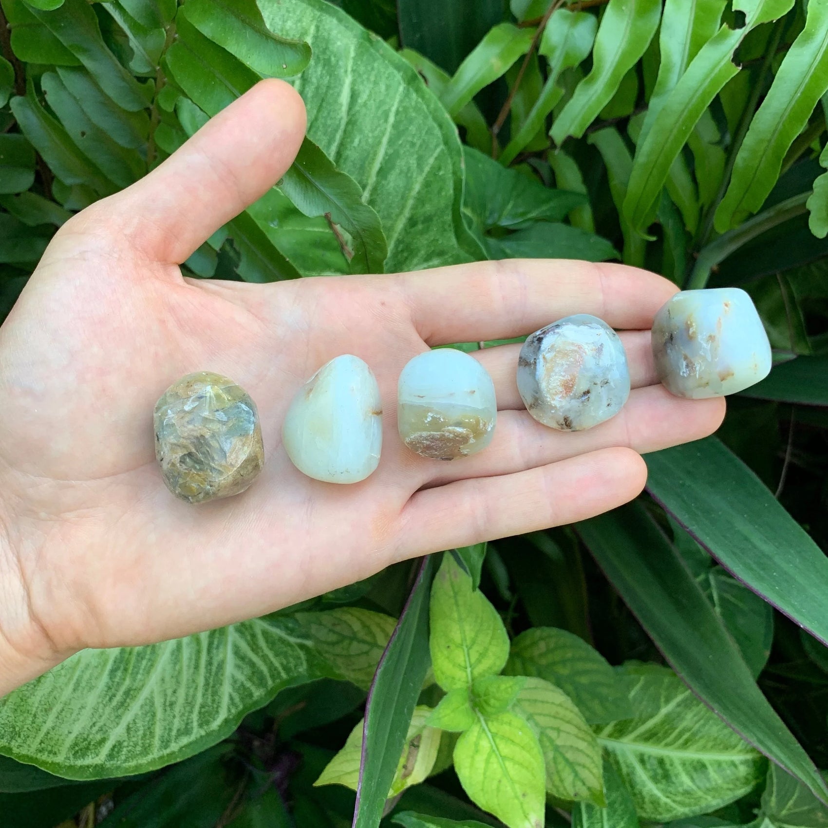 Resting display of Blue Opal tumbled stone, from Arequipa, Peru, shown for proportion against the hand.