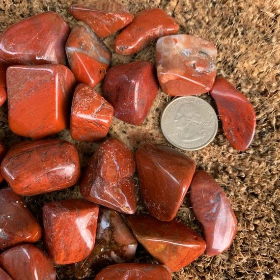 Studio-style view of Red Jasper tumbled stone, shown at hand scale.