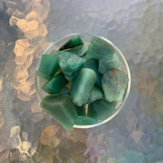 Set against a soft backdrop is an Aventurine raw crystal, linked to Love, with depth visible across the surface.