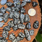 Edge view of Snowflake Obsidian tumbled stone, United States-sourced, showing earthy tone.