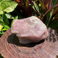 In-hand view of a Rose Quartz specimen held against natural backdrop.