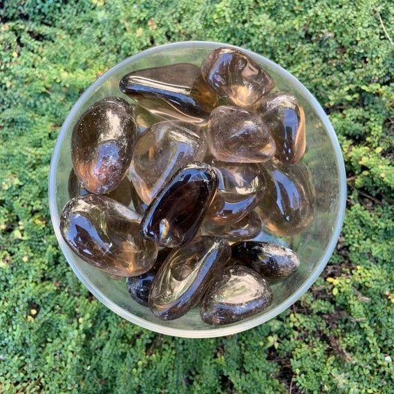 Held in hand, one Smoky Quartz tumbled stone for scale, sourced from Minas Gerais, Brazil.