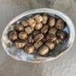 Size comparison with a Brown Aragonite tumbled stone held against natural backdrop.