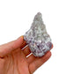 On a soft surface rests a Lepidolite specimen, with surface texture in view.