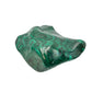 Angled view of the malachite specimen showing a cooler gray tone along the left edge of the banded face.