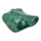 Angled view of the malachite specimen showing a cooler gray tone along the left edge of the banded face.