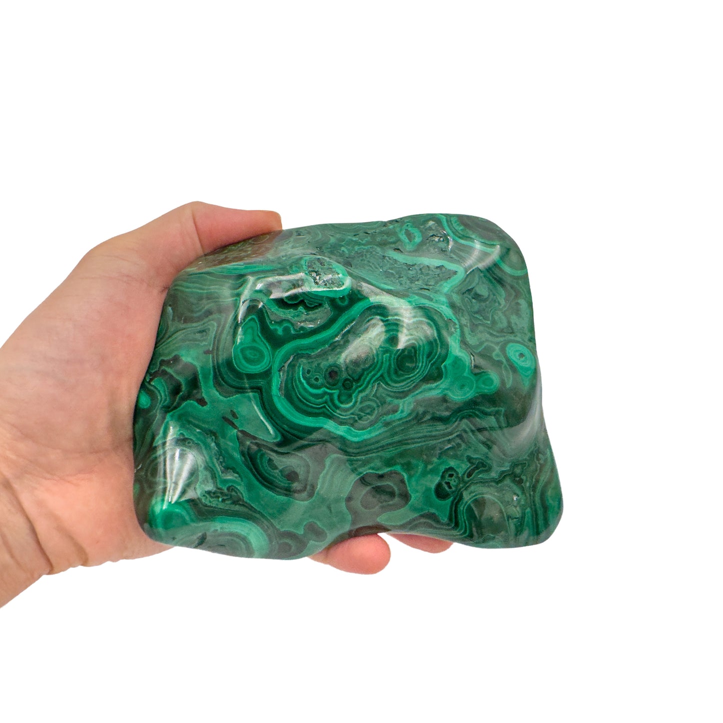 Malachite specimen held in hand for scale, showing the stone spans roughly 5 by 4 inches across its widest face.
