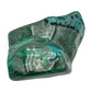 Wider angled view of the malachite specimen, showing concentric ring banding beside a raw patch at the upper left.