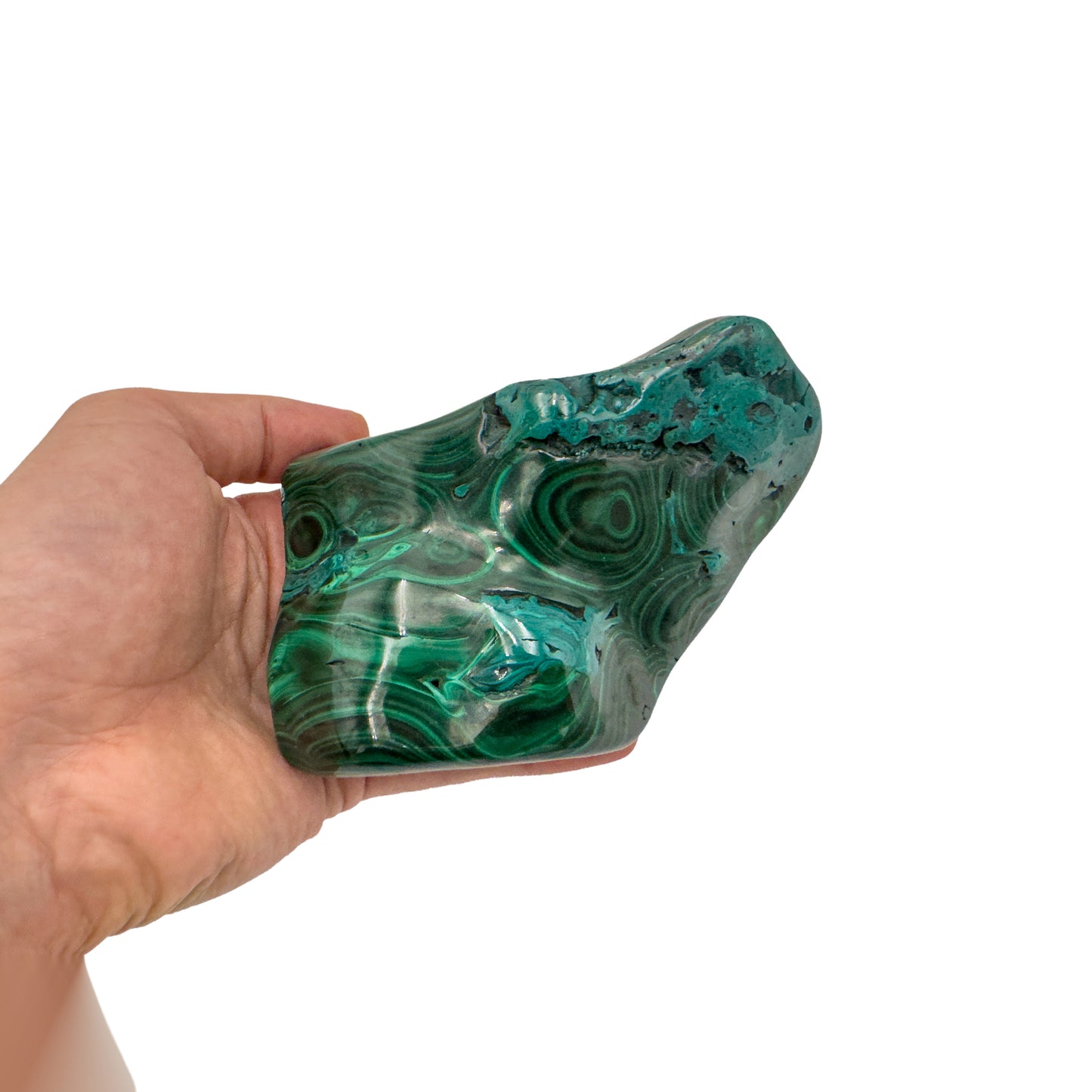 Malachite specimen held in hand for scale, showing the raw patch and banding at true size, just under 5 inches long.