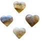Held in hand, a Natural Citrine polished heart held against natural backdrop.