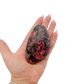 Rhodonite polished free form from Zimbabwe held in hand to show scale