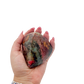 Rhodonite polished free form from Zimbabwe held in hand to show scale