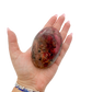 Rhodonite polished free form from Zimbabwe held in hand to show scale