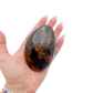 Rhodonite polished free form from Zimbabwe held in hand to show scale