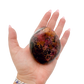 Rhodonite polished free form from Zimbabwe held in hand to show scale