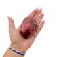 Rhodonite polished free form from Zimbabwe held in hand to show scale