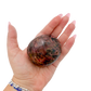 Rhodonite polished free form from Zimbabwe held in hand to show scale